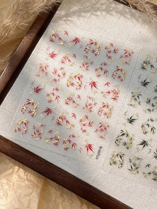 Detail of warm-toned bamboo and maple leaf nail stickers on rustic autumn background