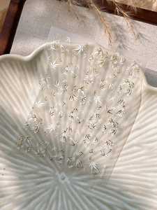 Detail of bamboo nail art stickers with white and gold leaf patterns on a ceramic tray