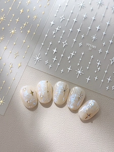 Gros plan de stickers à ongles étoiles avec motifs pailletés or et blanc sur les ongles