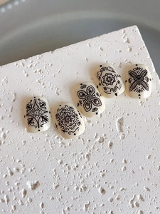 Detailed view of bohemian mandala pattern embossed on cream-colored press-on nails