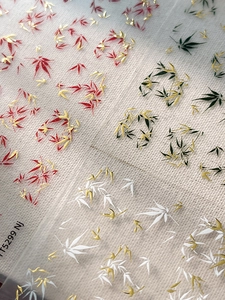 Macro detail of bamboo and maple leaf nail stickers with gold embossed foil texture