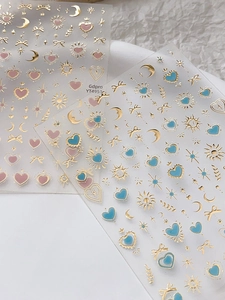 Vue détaillée des stickers nail art dorés avec motifs lune, étoiles et cœurs roses