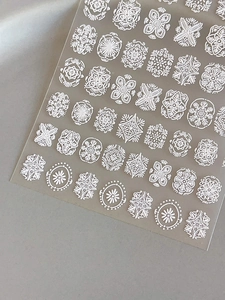 Detailed macro view of 3D embossed white bohemian floral and mandala nail art stickers