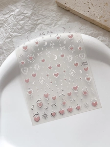 Détail d'autocollants pour ongles étoiles et lunes roses et argentés sur fond blanc