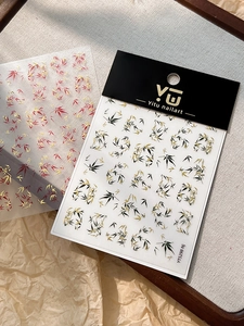 Detail showing gold bamboo and maple leaf nail stickers on elegant display cards