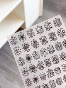 Macro detail of embossed bohemian nail stickers featuring black mandala and floral patterns