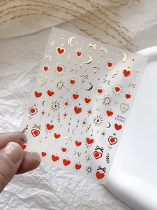 Détail macro de stickers ongles transparents avec motifs cœur lune et étoile dorés