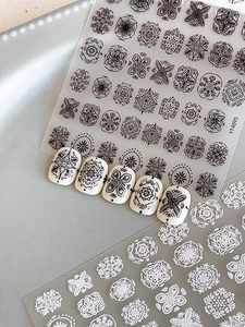 Detail of embossed bohemian nail art stickers with 3D white patterns on beige nails