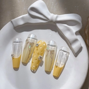 Magnifiques faux ongles jaune citron avec nœuds 3D et perles sur plateau en céramique