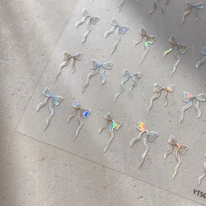 Stickers nail art 3D nœuds holographiques avec ruban irisé sur surface en pierre grise