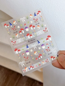 Macro shot of colorful mushroom and bow nail art stickers featuring cute character designs
