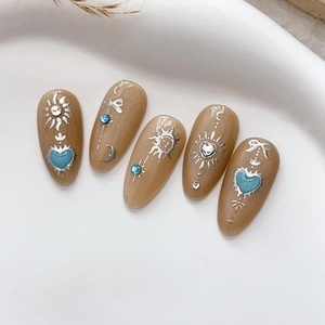 Faux ongles amande avec motifs dorés soleil lune et strass bleus brillants pour manucure