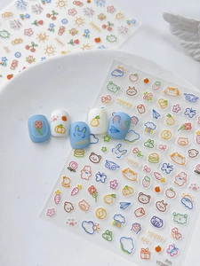 Detailed view of cartoon bunny and rainbow nail stickers with 3D sample art on blue nails