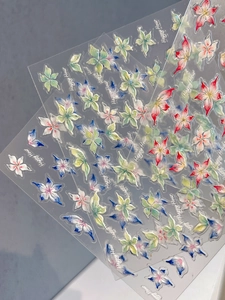 Vue macro de stickers d'ongles fleurs 3D avec effet nacre irisé et lettrage décoratif