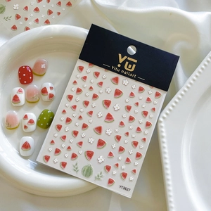 Détail d'autocollants pour ongles motif pastèque et fleurs blanches en relief sur plateau