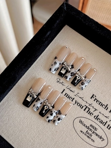 Détail de faux ongles nude avec pointes léopard noires et breloques de serrure argentées
