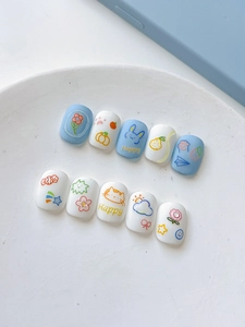 Detail showing blue and white press-on nails with cute hand-painted cartoon animals