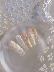 Macro shot of 3D butterfly charms and shell luster texture on pink gradient press-on nails
