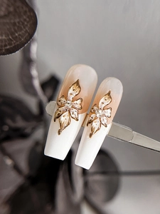 Detailed close-up of 3D gold-edged flower patterns on French gradient nail tips