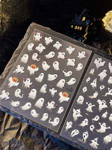 Détail d'autocollants à ongles pour Halloween avec fantômes et citrouilles sur ardoise noire