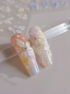 Detailed macro view of 3D white floral nail charms and rhinestones on gradient pastel nails