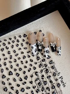 Détail de faux ongles léopard avec serrure en cœur argentée et nœuds décoratifs