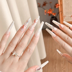 Detail view of long coffin press-on nails with white base and red plum blossom art