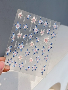 Gros plan de stickers 3D pour ongles à fleurs bleues et blanches au fini nacré iris