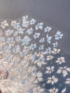 Detailed view of iridescent floral nail stickers with reflective laser petal patterns