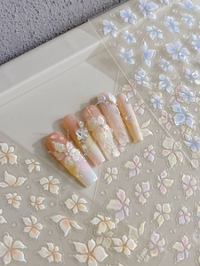 Macro detail of 3D floral nail charms with pearls and butterfly accents on gradient base