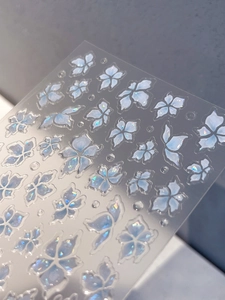 Detailed view of iridescent lily nail stickers with 3D shell texture on clear backing