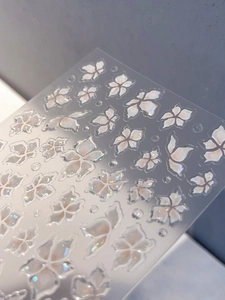 Macro detail of 3D lily flower nail stickers with iridescent pearl finish and embossing