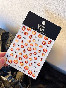 Detail view of Halloween pumpkin nail art stickers featuring jack-o'-lantern patterns