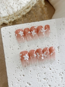 Detail of pink gradient press-on nails with 3D floral art, pearls and gold foil accents