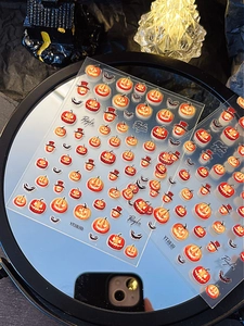 Detail of Halloween nail stickers featuring pumpkins and bats on a decorative mirror base