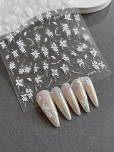 Vue macro de stickers 3D blancs pour ongles avec détails de fleurs en relief sur ongles amande