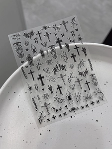 Detail view of gothic nail art stickers featuring crosses, spiders and black graffiti designs