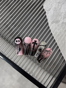 Detail view of Gothic Halloween nail stickers with skull, cross, and coffin art on pink gradient