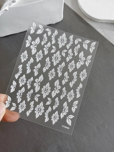 Close-up of 5D embossed nail stickers featuring white 3D floral and leaf textures