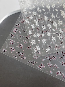 Détail d'autocollants 5D pour ongles avec fleurs blanches et violettes peintes à la main