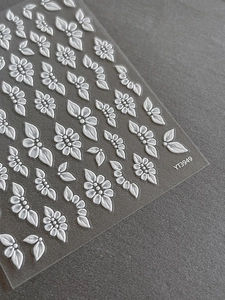 Detailed macro view of 3D embossed white floral nail stickers with relief texture