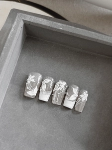 Detail of 3D embossed white flowers and pearls on silver glitter nail stickers
