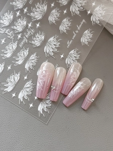 Detailed view of white floral embossed nail stickers on elegant pink gradient nails