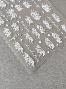 Detailed view of white floral nail stickers with stars and text on a textured surface