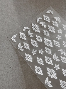 Macro shot of 5D embossed white flower nail stickers with intricate floral petal details