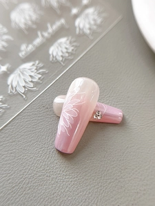 Detailed macro view of white flower nail art stickers on pink gradient press-on nails