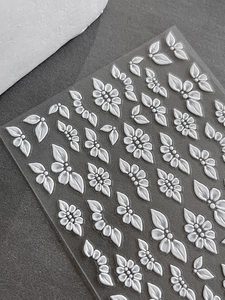 Detailed macro view of 5D embossed white floral nail art stickers with relief textures