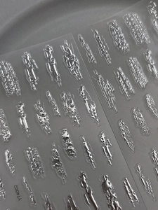 Makro-Detail von 3D-Silber-Metallic-Nagelstickern auf einer transparenten Folie