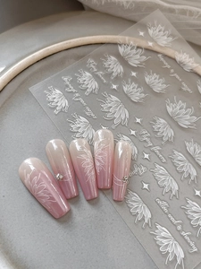 Detail of white floral nail stickers on pink gradient nails with micro rhinestones