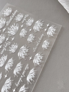 Macro detail of white floral nail art stickers with embossed lotus and star designs